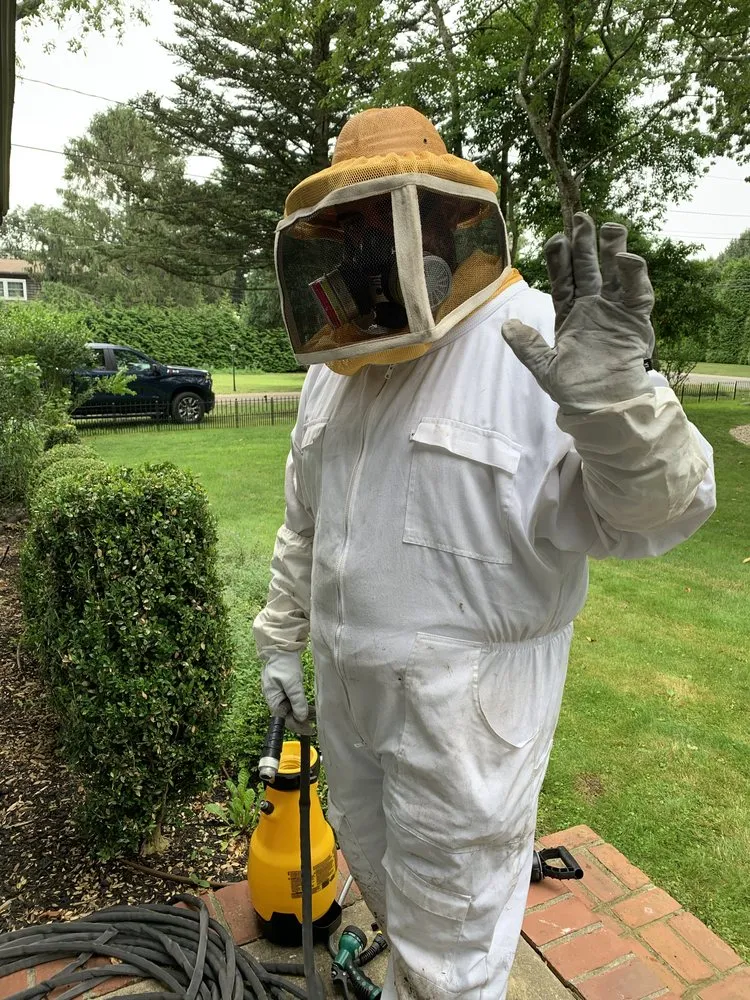 Technician in full protective equipment with a pump sprayer before an outdoor mosquito treatment