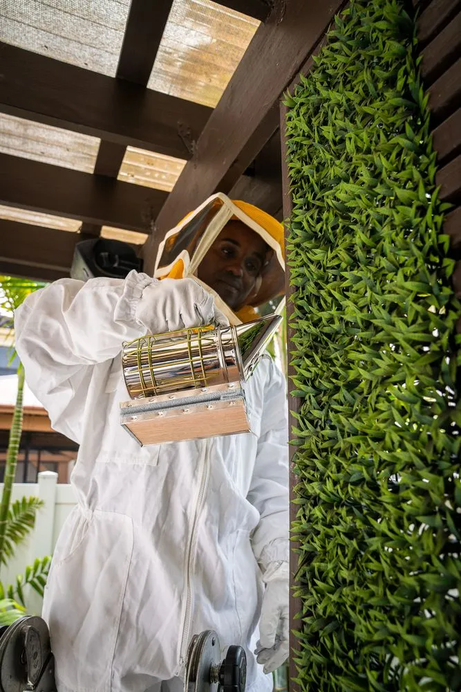 Technician in a full protective suit holding a smoker before a stinging-insect removal